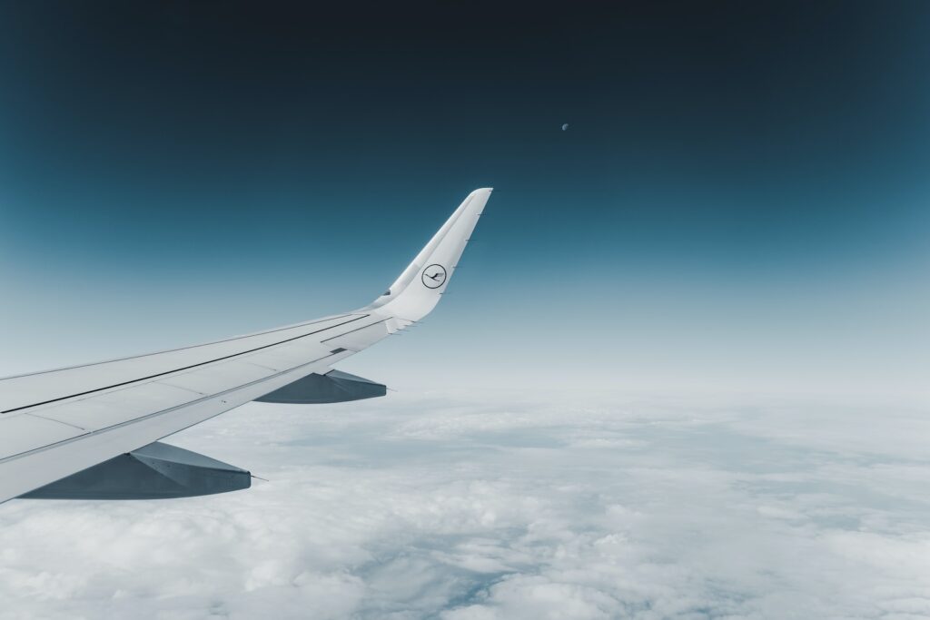 white airplane flying over the clouds